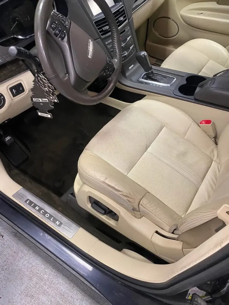 Driver footwell and seat after interior detailing, clean carpet and door sill