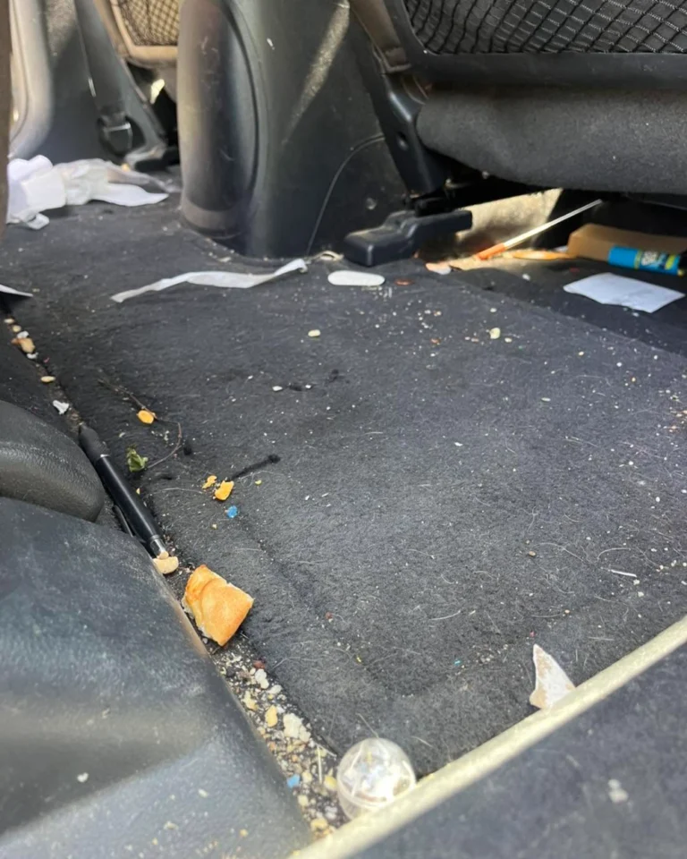 Rear car floor covered in trash and debris before interior detailing