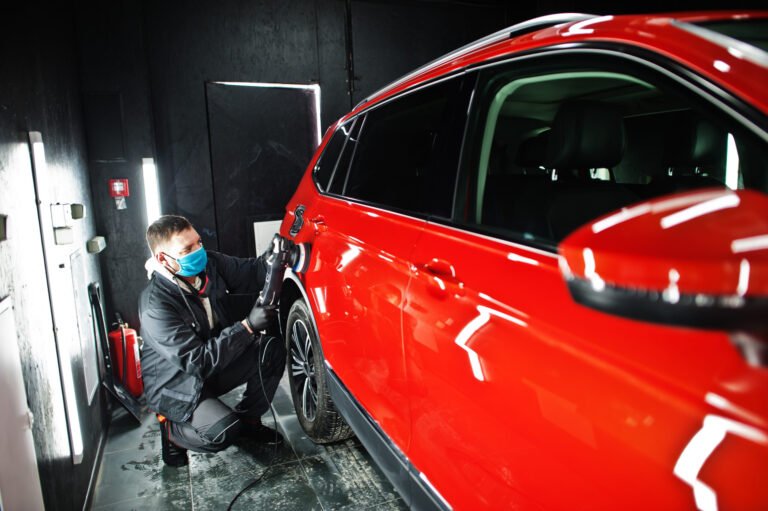 Bear Creek Car Detailing detailer hand polishing a red car in Medford, Oregon